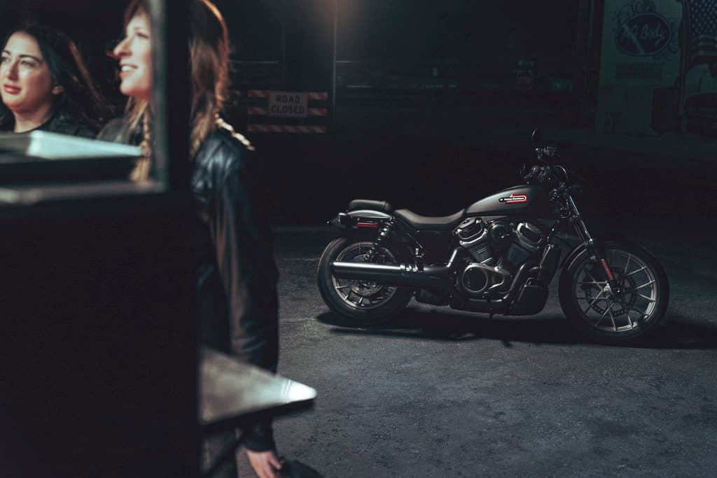 23-rh975-nightster-special-lifestyle-bc-0014.jpg Due donne in abbigliamento in pelle, una sorridente, con una moto Harley-Davidson scura parcheggiata di notte. Rappresenta il lifestyle dei