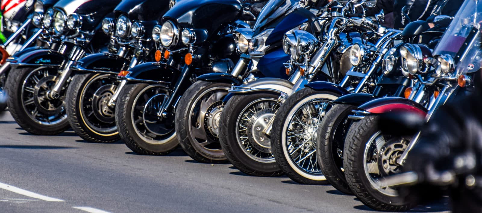 Motorcycle rims in the festival Allineamento di motociclette Harley-Davidson e cruiser, con fari, parafanghi e ruote anteriori in evidenza. Dettagli cromati e design iconico.