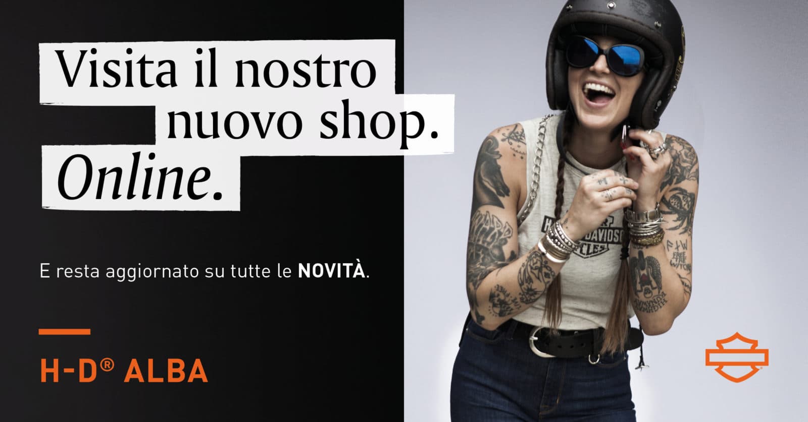H-DAlba_Social_ecommerce_FB.jpg Pubblicità Harley-Davidson Alba: donna sorridente con casco e occhiali, braccia tatuate, indossa abbigliamento H-D. Invito a visitare il nuovo shop online per novità.