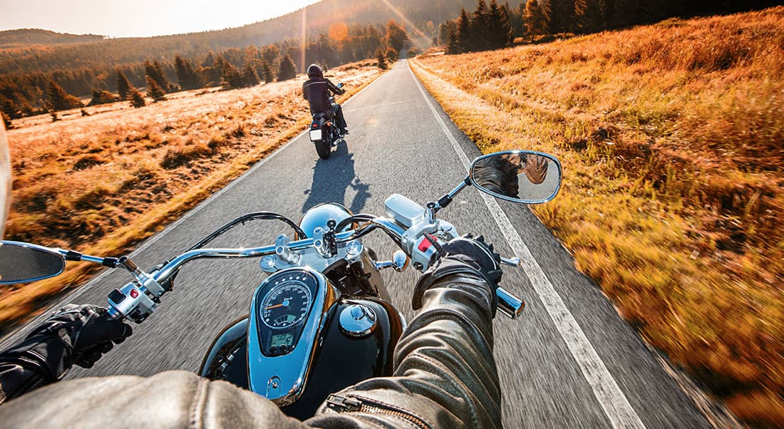 Harley-Davidson-Softail-2018 Vista in prima persona di un motociclista su strada panoramica, seguendo un'altra moto. Manubrio, strumentazione e abbigliamento. L'