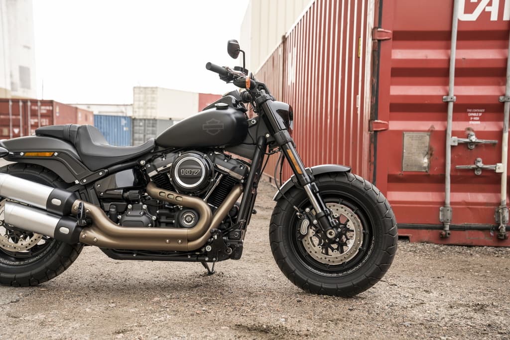 Model Year 2019 GAP Photography. INTERNATIONAL ONLY Harley-Davidson Fat Bob 107 nera opaca, motore Milwaukee-Eight, scarichi doppi, pneumatici larghi, in contesto industriale. Prenota un test ride.