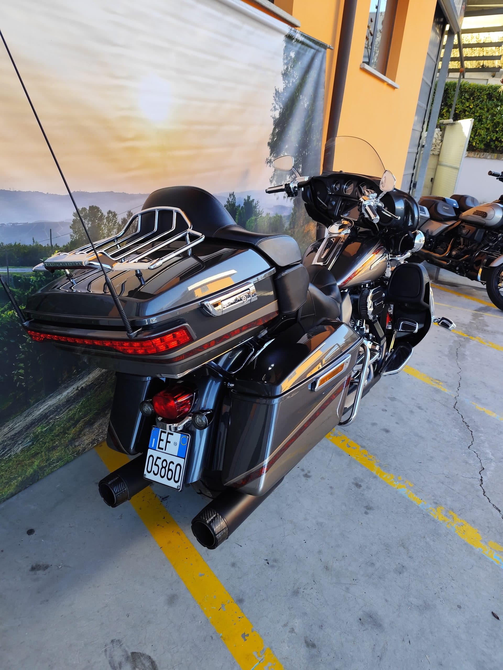 IMG_20260217_091402.jpg Harley-Davidson touring grigio scuro, modello bagger, con portapacchi cromato, borse laterali e scarichi neri. Targa italiana EF 05860. Esposta in concessionaria.