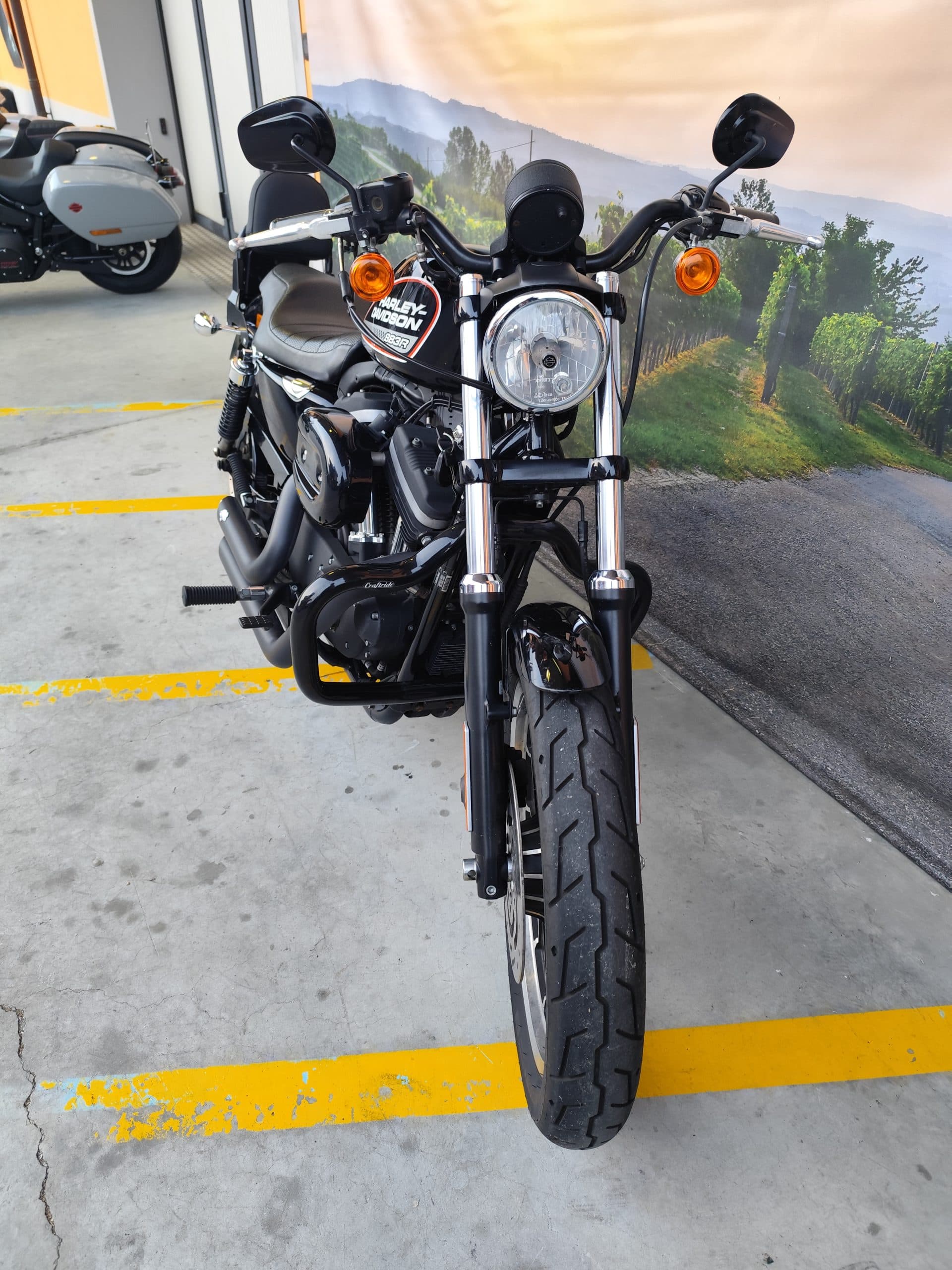 IMG_20260303_180135.jpg Harley-Davidson Sportster 883R nera, vista frontale, con faro tondo e forcelle cromate, esposta in concessionaria. Ideale per test ride.