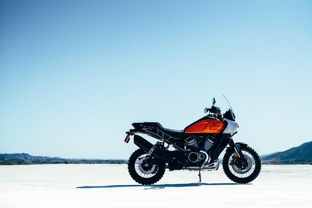 PA1.jpg Harley-Davidson Pan America arancione e nera su distesa desertica sotto cielo azzurro, pronta per l'avventura e test ride.