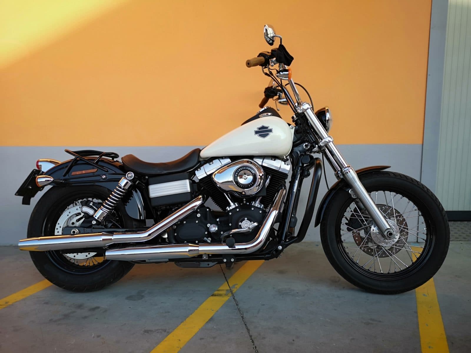 rpt Harley-Davidson Dyna Street Bob con serbatoio bianco, motore V-Twin, scarichi cromati e manubrio mini-ape, parcheggiata.