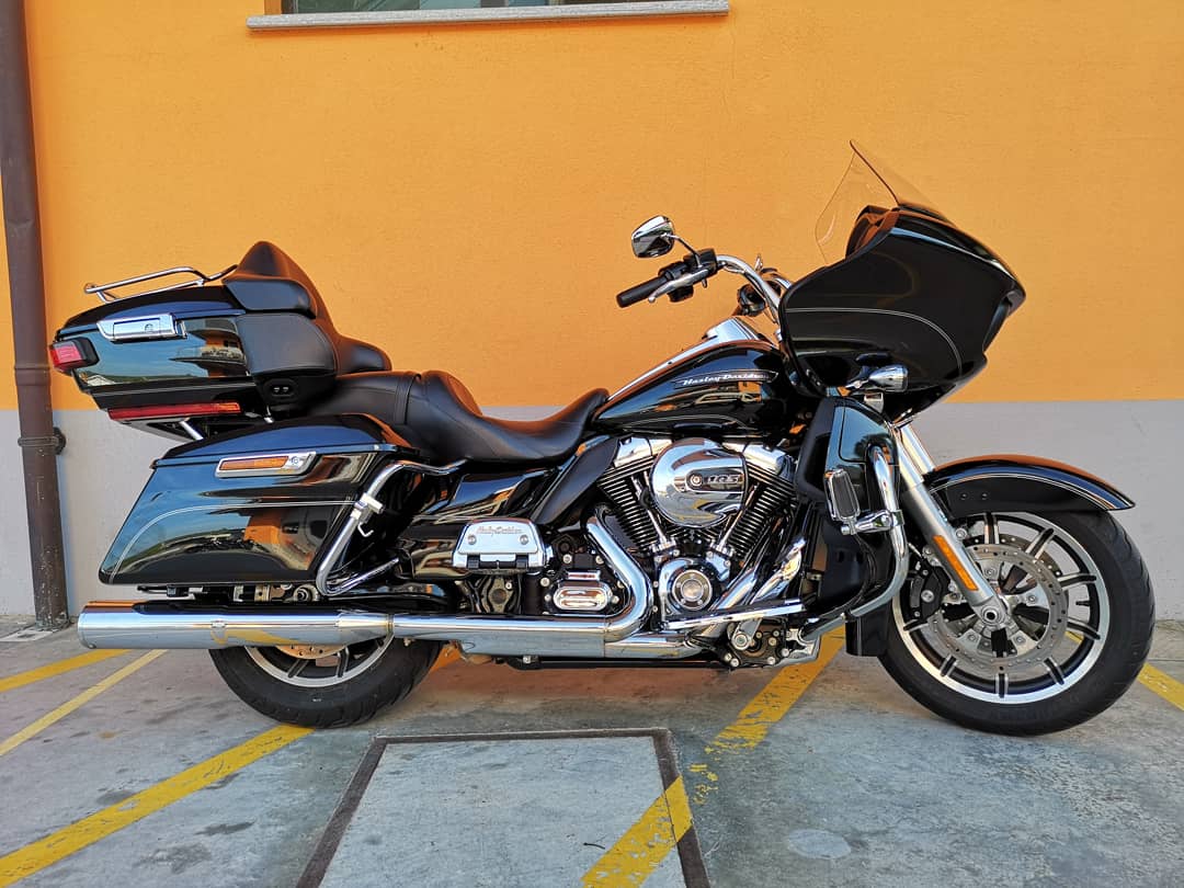 ef86524.jpg Harley-Davidson touring nera lucida, motore cromato, borse laterali e top case, parcheggiata su asfalto. Ideale per test ride.