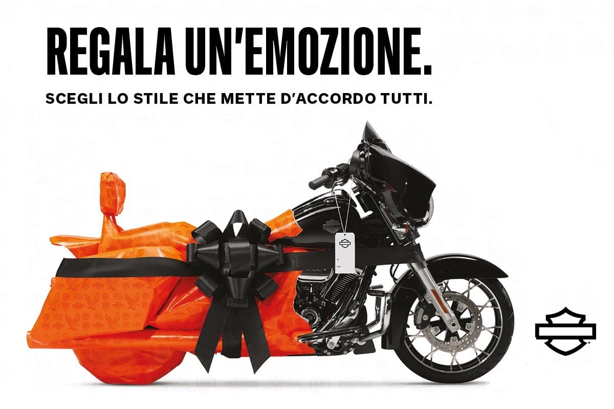 h-d_finalholiday_billboard_1200800.jpg Harley-Davidson, moto nera avvolta in carta regalo arancione con fiocco nero. Messaggio: Regala un'emozione.
