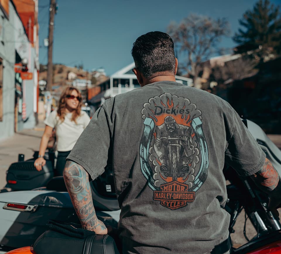 Abbigliamento Harley-Davidson: stile in sella Uomo su moto Harley-Davidson, di spalle, con t-shirt grigia. Stampa posteriore: logo