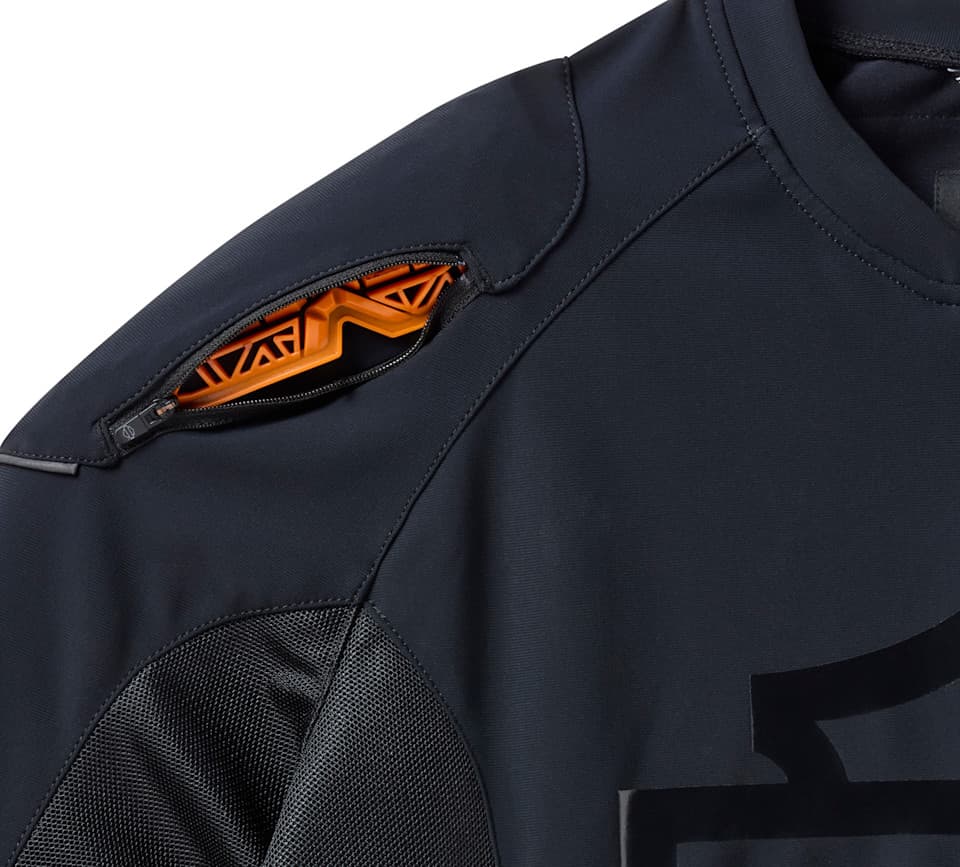 Abbigliamento tecnico moto Harley-Davidson con protezione Abbigliamento tecnico Harley-Davidson nero. Dettaglio spalla con cerniera e inserto protettivo arancione. Tessuto traspirante e mesh per comfort e sicurezza in moto.